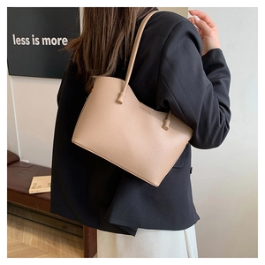 Gros plan d'un sac cabas kaki minimaliste en cuir grainé porté à l'épaule par un mannequin