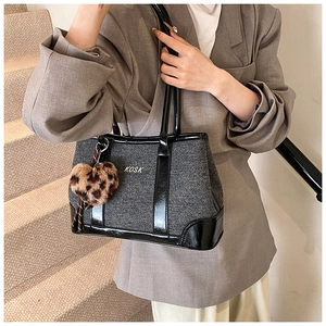 Detail of grey twill tote bag with KOSK logo, black leather trim and leopard heart charm