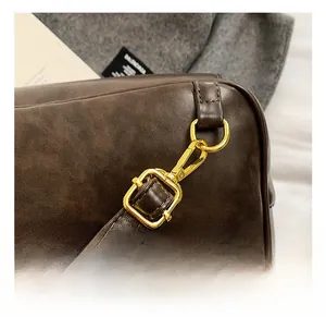 Detail of vintage brown leather bag showing premium gold spring hook and strap attachment