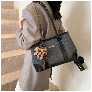Detail of grey fabric tote bag with black leather trim and leopard heart charm