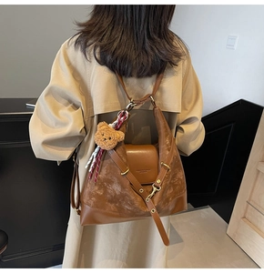 Detail of vintage brown tote bag with adjustable strap and plush bear accessory