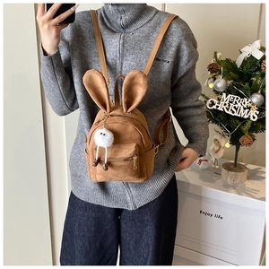 Vue portée du mini sac à dos en daim marron avec oreilles de lapin et pompon peluche