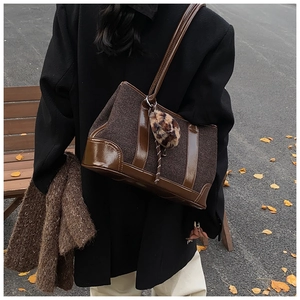 Detail of dark brown tweed tote bag with leather trim and leopard plush charm