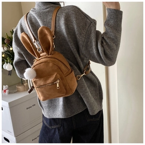 Vue détaillée d'un mini sac à dos en daim marron avec oreilles de lapin et pompon blanc