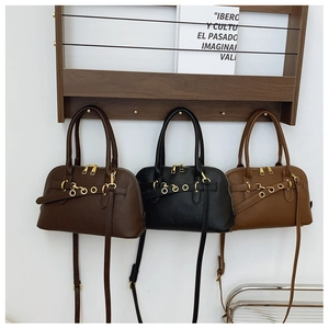 Three vintage shell-shaped bags in black, coffee, and caramel colors on a wooden stand