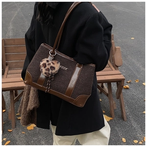 Detail of woven brown tote bag featuring leopard print heart charm and KOSK lettering