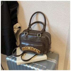 Close-up of vintage brown leather Boston bag with plush Holiday lettering and gold hardware