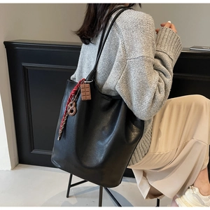Vue détaillée du grand cabas en cuir noir avec foulard et breloque porté par le mannequin