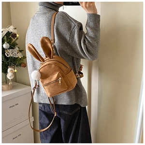 Détail d'un mini sac à dos en daim marron avec oreilles de lapin et pompon blanc doux