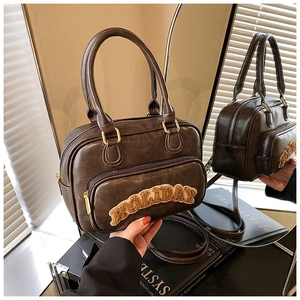 Close-up of vintage brown Boston bag with plush letter patches and double handles