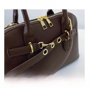 Close-up of golden metal zippers and hardware accents on a dark brown vintage handbag