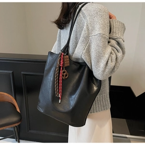 Détail d'un grand sac cabas noir avec pendentif chocolat et corde tressée décorative