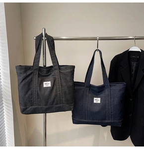 Detail of grey and blue denim tote bags with exterior pockets on a display rack