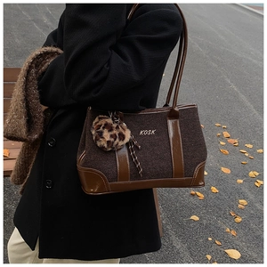 Detail of dark brown tote bag in textured fabric and leather with gold KOSK logo