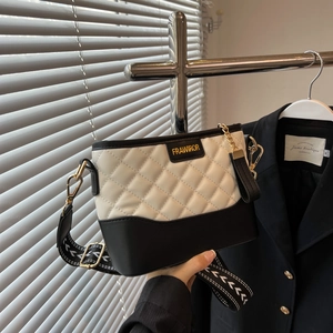 Detail of black and white quilted crossbody bag with gold hardware and wide strap