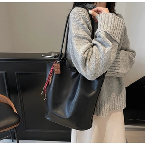 Détail d'un grand cabas noir en cuir avec breloque chocolat et corde à carreaux