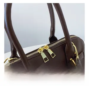 Detailed close-up of the smooth golden double zippers on a brown vintage shell bag