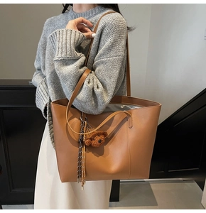 Vue détaillée du sac cabas en cuir mat marron avec breloque ours et pompon tissé