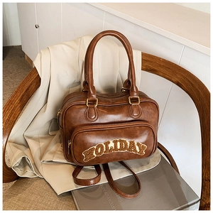 Detail of vintage brown leather handbag with plush Holiday embroidery and front pocket
