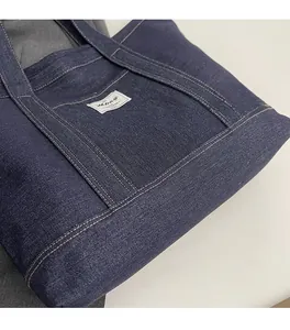 Macro detail of dark blue denim tote bag fabric with contrast yellow stitching