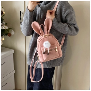 Détail d'un sac à dos rose à oreilles de lapin avec charm en peluche et zips dorés