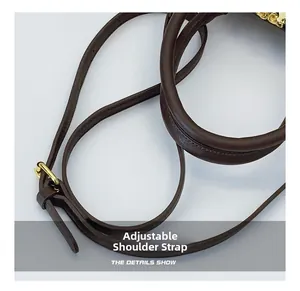 Close-up of adjustable leather shoulder strap and golden buckle on coffee handbag