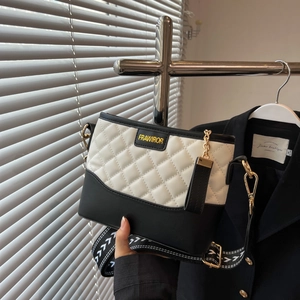 Detail of quilted leather crossbody bag with gold hardware and woven geometric strap