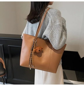 Sac fourre-tout en cuir marron avec pendentif ours porté par un mannequin au quotidien
