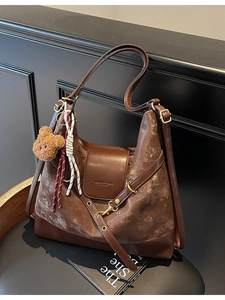 Retro brown velvet tote bag with leather trim and bear pendant on black chair
