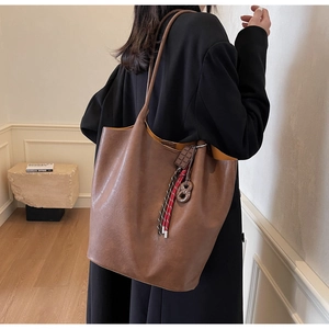 Sac cabas marron en cuir avec pompon tressé coloré et doublure jaune sur modèle