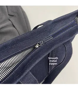 Detailed close-up of the silver metal zipper and striped lining on denim tote bag