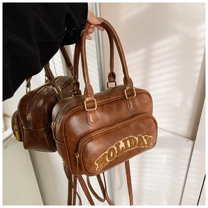 Detail of vintage brown PU leather handbag with white HOLIDAY embroidery and gold hardware