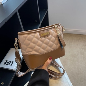 Detailed view of quilted faux leather bag with contrast stitching and metal logo