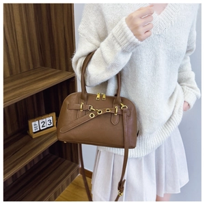 Detail view of a vintage brown shell-shaped handbag with decorative straps and gold zippers