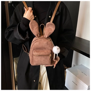 Vue détaillée mini sac à dos en daim marron avec oreilles de lapin et charme en peluche