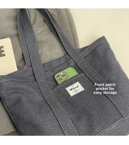 Detail of blue denim tote bag showing a functional front patch pocket for easy storage