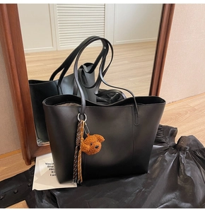 Détail d'un sac cabas en cuir noir avec un charmant pendentif chien en peluche