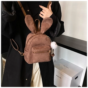 Détail d'un mini sac à dos en daim marron avec oreilles de lapin et pompon en fourrure blanc