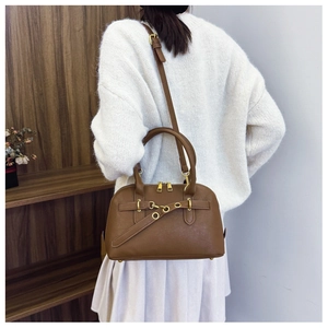 Retro brown leather Boston bag with gold metal rings shown on model in a warm room