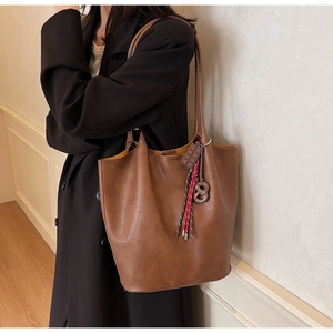 Détail d'un sac cabas marron foncé avec des charms originaux en chocolat et bretzel