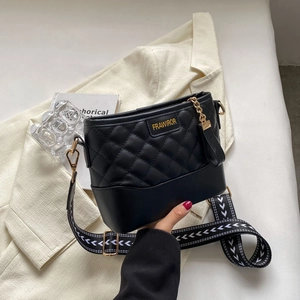 Detail of black quilted shoulder bag with gold lettering and patterned strap