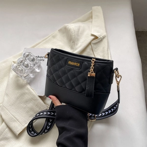 Detail of black quilted crossbody bag with golden logo plaque and woven strap