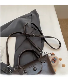 Detail of dark brown leather tote bag showing the adjustable shoulder strap and plush charm