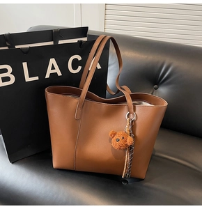 Détail d'un grand sac cabas en cuir caramel avec bandoulières et pendentif ours en peluche