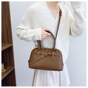 Detail of a brown vintage shell bag with gold hardware and horizontal decorative strap
