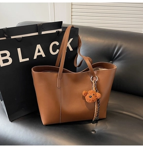 Sac cabas en cuir marron sur canapé noir avec un pendentif d'ours mignon et élégant