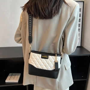 Detail of quilted two-tone crossbody bag with wide patterned strap and golden metal chain