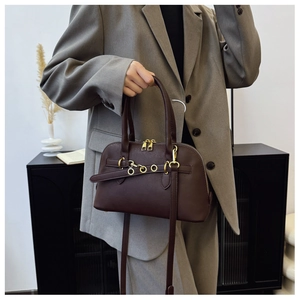 Detail of dark chocolate retro shell bag with golden rings and adjustable shoulder strap