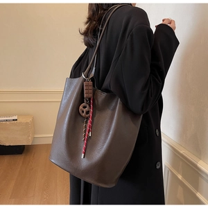 Détail du sac cabas marron foncé sur modèle avec cuir mat et pendentifs créatifs