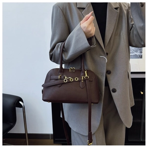 Detail of dark brown leather Boston bag with metal eyelets and gold zippers on a model